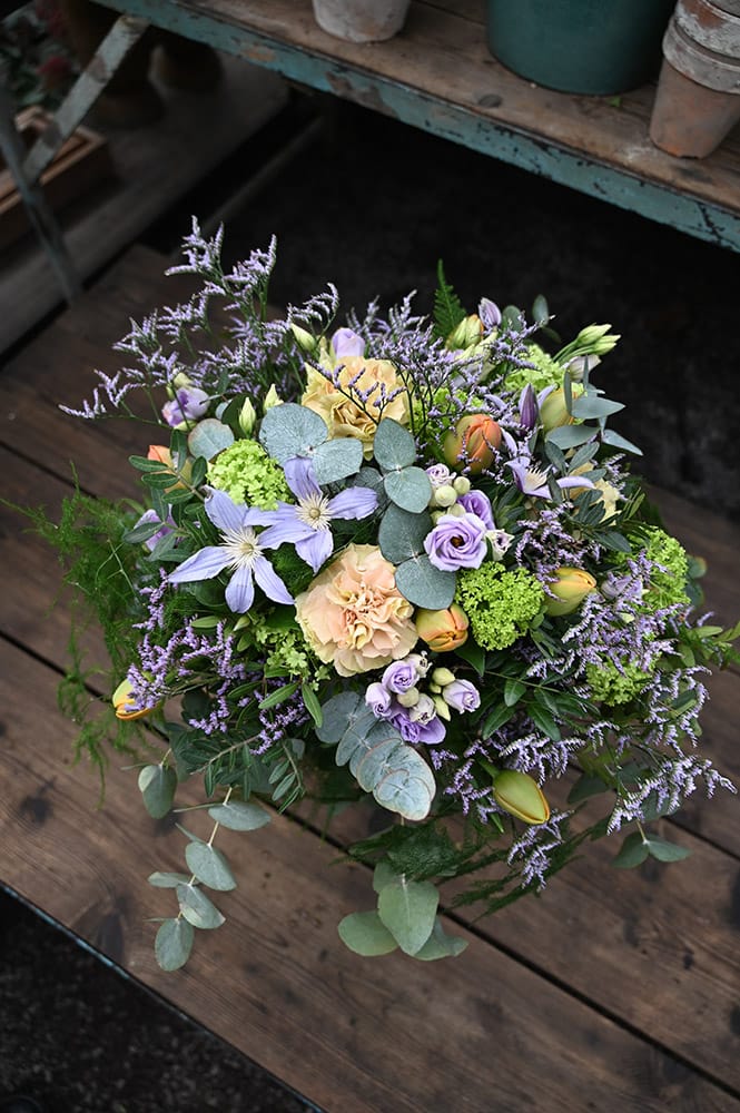 Bukett med snittblommor i lila och aprikos-toner